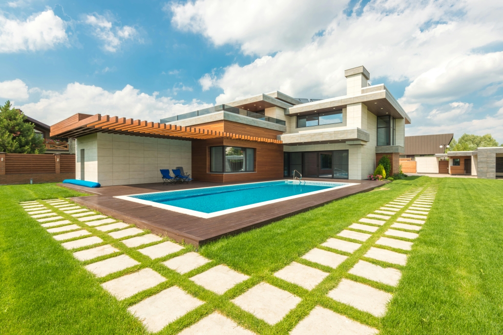 A modern luxury home featuring a backyard swimming pool and wooden decking. A valid Pool Safety Certificate QLD is required for such properties to ensure fences and barriers meet current safety legislation.