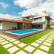 A modern luxury home featuring a backyard swimming pool and wooden decking. A valid Pool Safety Certificate QLD is required for such properties to ensure fences and barriers meet current safety legislation.