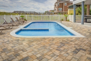 A modern luxury home featuring a backyard swimming pool and wooden decking. A valid Pool Safety Certificate QLD is required for such properties to ensure fences and barriers meet current safety legislation.